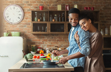 Loving black wife and husband preparing dinner in kitchen