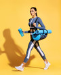 Go to gym! Attractive latin woman in fashionable sportswear on yellow background. Dynamic movement. Side view. Sports and healthy lifestyle