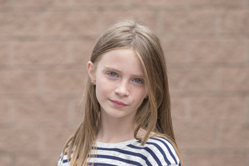 Beautiful blond young girl with freckles outdoors on wall background, closeup portrait