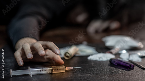 Fotografía Male junkie hand trying to grab injection syringe of cooked heroine