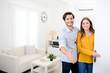 © W PRODUCTION - cheerful young couple man and woman welcome friends at open front door new student home apartment