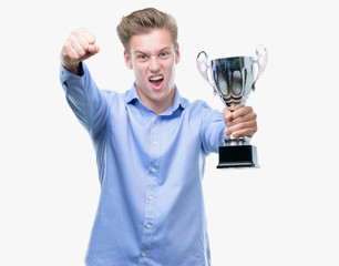 Canvas Print - Young handsome blond man holding a trophy annoyed and frustrated shouting with anger, crazy and yelling with raised hand, anger concept