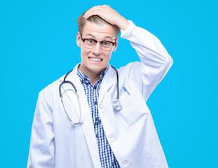 Canvas Print - Young handsome blond doctor stressed with hand on head, shocked with shame and surprise face, angry and frustrated. Fear and upset for mistake.