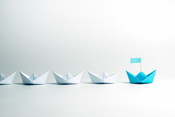 Wall Mural - Leadership concept. Blue leader paper ship leading among white on white background.