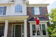 Man washing the soffits or eaves of a modern house