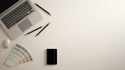 Stylish minimal office table desk. Workspace with laptop, notebook, pencils and sample color palette on white background. Flat lay, top view