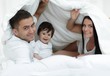 © ASDF - Families with children in bed under a blanket
