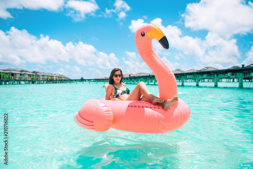 Fotomural Beautiful young woman posing in sensual swimsuit sitting on a flamingo