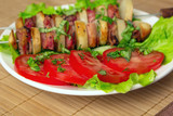 Fototapeta Las - chicken kebab with bacon potatoes, herbs and tomatoes