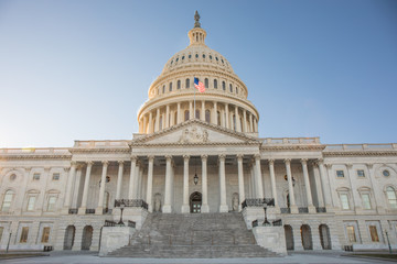 Wide view of the front of the US Capitol Building in Washington, DC without any people and a bright blue sky.