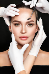 Beautiful woman portrait with classical make up and hands in medical gloves with cosmetic tool.