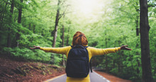 Tourist Traveler With Backpack With Raised Hands, Girl Hiker View From Back Looking Into Road At Forest With Arms Outstretched And Enjoying The Breath Of Fresh Clean Air In Trip, Relax Holiday Concept