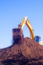 A Large Iron Excavator Bucket Collects And Pours Sand Rubble And Stones In A Quarry At The Construction Site Of Road Facilities
