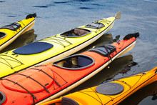 Colorful Orange And Yellow Kayaks Floating In The Blue Water