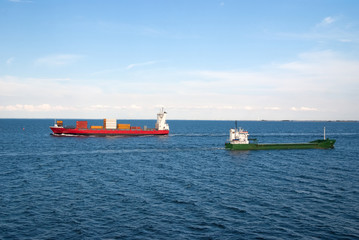 Barges ship cargo containers in sea in Copenhagen, Denmark. Cargo ships float in blue sea on idyllic sky. Marine transport and transportation. Shipping and shipment. Logistics