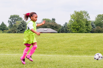 Wall Mural - A young girl is learning how to play soccer