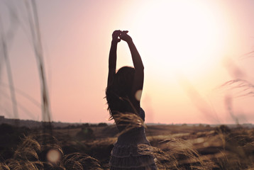 Silhouette of happy women  in grass field at sunset. Summer happiness