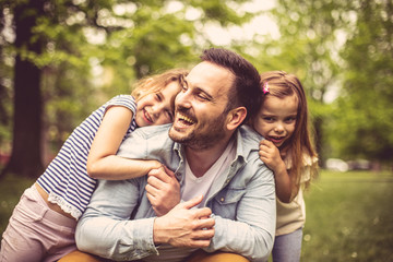 Wall Mural - Father with daughters at park.