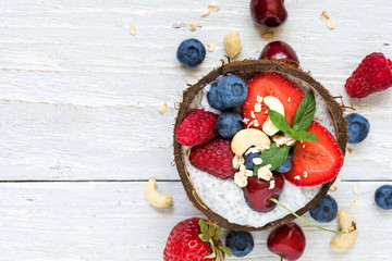 Wall Mural - chia pudding with fresh berries, nuts, oats and mint in coconut bowl. healthy breakfast