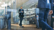 © Gorodenkoff - Stylish Suited Businessman Uses Smartphone Rides Skateboard Through the Corporate Building Hallway. Stylish Glass and Concrete Building with Multicultural Crowd of Business People.