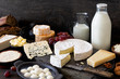 Cheese, milk and dairy products on rustic dark wood and slate background.