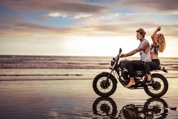 side view of couple riding motorcycle on ocean beach