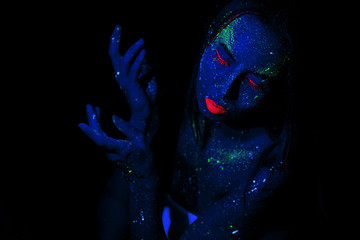 Wall Mural - A girl with blue skin and cosmetic make-up, made of neon and fluorescent paints. The concept of star space in a person. Magic fantasy and dreams.