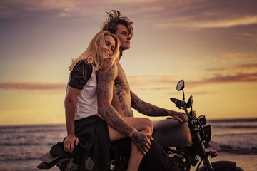 happy girlfriend leaning on boyfriend shoulder on motorcycle on ocean beach