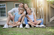 © goodluz - Happy family of four sitting in yard
