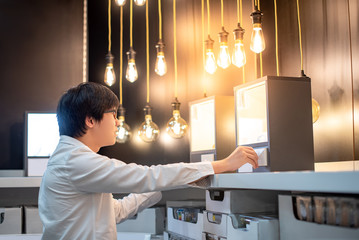 Young Asian man choosing package of electrical light bulb, furniture home decoration shopping concept