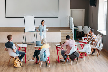 Wall Mural - group of young students sitting in class and listening to lecture