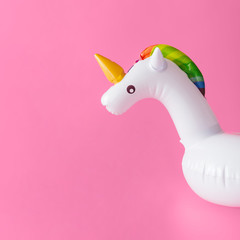 Inflatable unicorn pool toy on pastel pink background. Minimal summer concept.