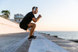 © LIGHTFIELD STUDIOS - side view of sporty adult man in headphones jumping on parapet on seashore