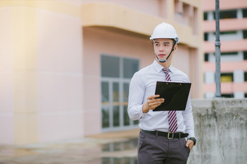  A handsome young engineer stands tall and holds a document.