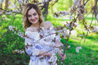 © Alexander - Beautiful blonde girl with blond hair in a dress on a background of spring blooming trees