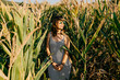 © lubero - Young pretty woman standing in a green and yellow corn field. She is very happy, relaxed and carefree. Feel concept. Lifestyle.