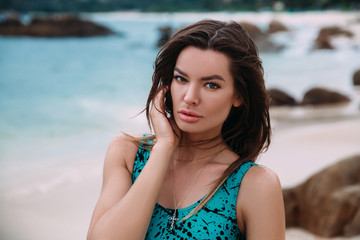 Wall Mural - Portrait of a dark-haired beautiful woman, resting on the beach, the wind develops her long hair, the concept of rest, hotels, travel.