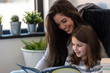 © lordn - Girls having fun at home. Portrait of mother and daughter reading a book