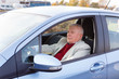 © kulniz - Old senior man sitting in car on driver seat and keeps the steering wheel. Spring and summer time
