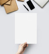 © ifriday - Hands holding blank paper sheet A4 size at table work space top view.
