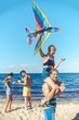 © LIGHTFIELD STUDIOS - selective focus of interracial group of friends with kites having fun on sandy beach