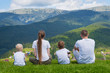 © somemeans - Family holiday. Parents and two sons admire views of the mountains. Back view. Sunny summer day