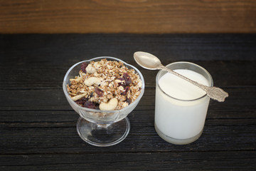 Granola with berries and yogurt on a black wooden table. Traditional American Breakfast