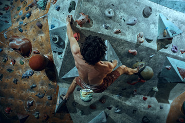 Wall Mural - Free climber young man climbing artificial boulder indoors