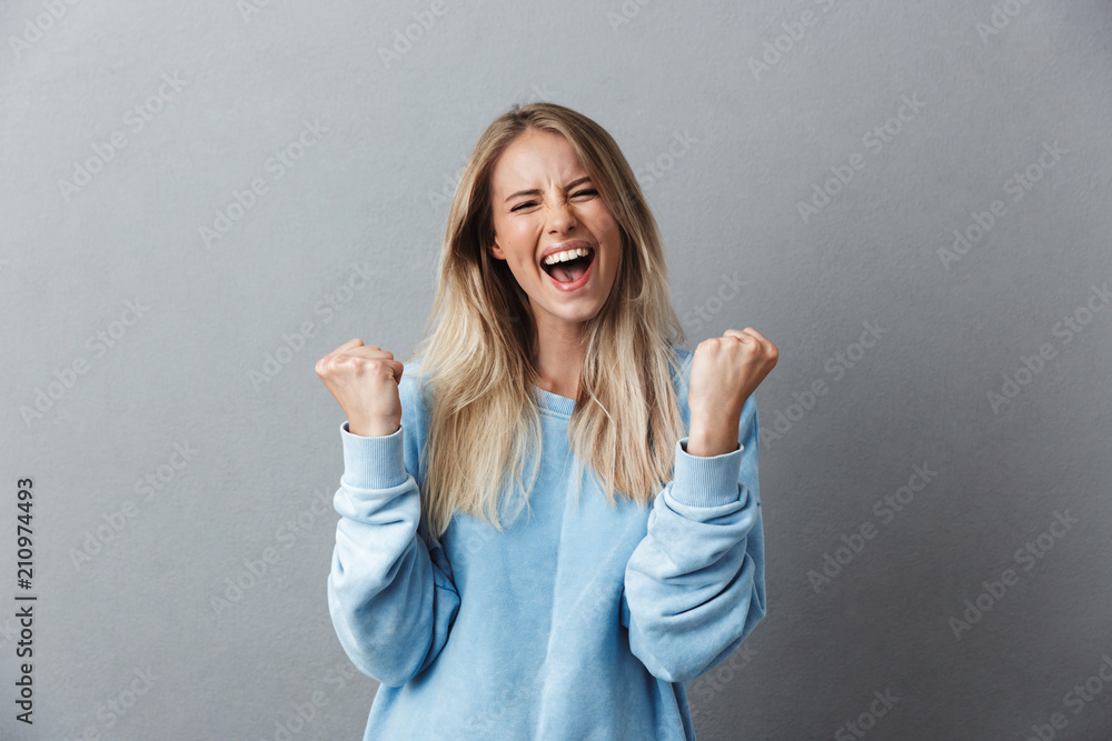 Portrait of a happy young blonde girl celebrating success - obrazy, fototapety, plakaty 