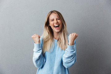 Wall Mural - Portrait of a happy young blonde girl celebrating success