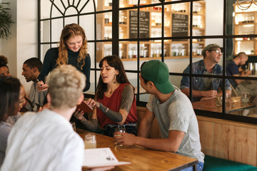 Wall Mural - Diverse group of friends ordering food in a trendy bistro