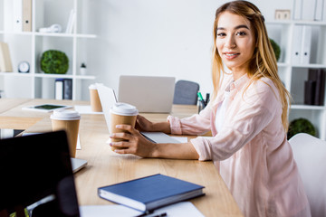 Wall Mural - smiling asian businesswoman working on start up project and looking at camera in office