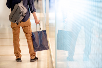 Closeup of male hand holding blue shopping bag in department store. Urban lifestyle in shopping mall concept