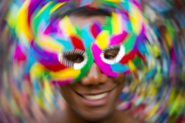 Salvador Carnival scene features samba dancing Brazilian man smiling in colorful mask in Pelourinho, Slow shutter speed and motion blur